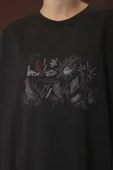 Remera negra de corte oversize con estampado abstracto en tonos rojos, grises y blancos.