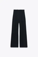 Pantalón negro de tiro alto y corte acampanado, con cierre frontal de cremallera dorada.