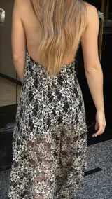 Vestido midi de encaje floral color beige sobre base negra, con cuello halter y falda con vuelo.