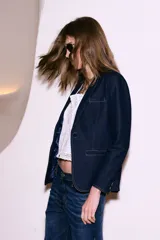 Blazer azul marino de denim con forro azul satinado, solapas de muesca, cierre frontal con un botón, bolsillos delanteros con solapa y puños con botones.