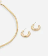 Conjunto de collar y aros dorados con diseño orgánico. El collar es de cadena fina con dije rígido y los aros son tipo argolla.