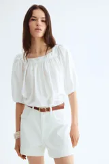 Blusa corta blanca de tejido liviano con escote cuadrado fruncido, corte holgado, manga globo raglán al codo y elástico fino en los puños.
