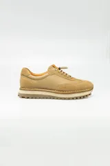 Championes de cuero color beige, de estilo casual, con cordones elastizados y suela de goma.