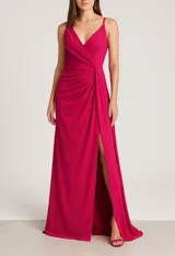 Vestido largo de fiesta color fucsia, con breteles finos, escote en V cruzado, drapeado en la cintura y tajo lateral alto.