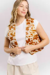 Chaleco de cuero con estampado de vaca en tonos marrón y blanco, de corte recto y largo a la cintura. Su diseño abierto en el frente lo convierte en una prenda versátil, fácil de combinar tanto con básicos como con looks más elaborados.