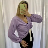 Remera de manga larga color lila con escote en V y frunce central ajustable con cordones.