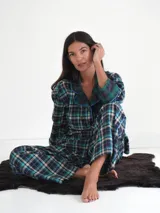 Conjunto de pijama a cuadros con ribetes en color lila, compuesto por camisa de manga larga con botones y pantalón largo.