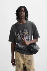 Camiseta negra con cuello redondo y mangas cortas. Estampado frontal con la frase "Cherry Pill Blush Delight" y una ilustración de una mujer en un cohete. Tiene un efecto de lavado que le da una apariencia única.