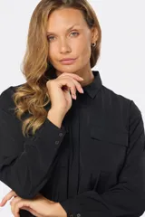 Blusa tipo camisa blanca con estampado de pequeñas flores negras, manga larga, botones nacarados ocultos con cartera y doble capa en el frente para evitar transparencias.
