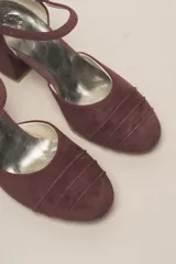 Zapato de tacón de terciopelo verde con correa al tobillo, punta redondeada y tacón cuadrado.