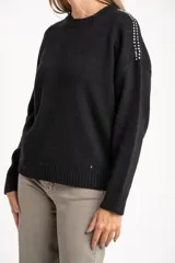 Sweater de punto negro, corte oversize, con cuello redondo y apliques de tachas plateadas en los hombros.
