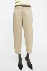 Pantalón chino color amarillo claro, de tiro medio, con bolsillos frontales y traseros. Incluye cinturón trenzado marrón.