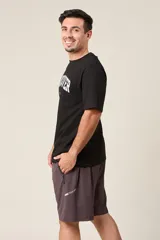 Bermuda deportiva gris de nylon, de corte suelto, con cintura elástica y cordón de ajuste. Cuenta con detalles de líneas negras en los costados y bolsillos laterales con cierre.