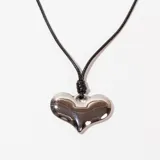 Collar con dije de corazón plateado y cordón negro.