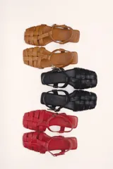 Sandalias franciscanas rojas de cuero con tiras entretejidas y hebilla lateral.