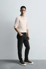 Pantalón de jean azul oscuro con efecto lavado y roturas en las rodillas, de corte ajustado al cuerpo desde la cintura hasta el tobillo.