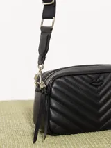 Bandolera color beige con diseño acolchado en forma de V y logo metálico dorado en forma de labios. Tiene correa larga ajustable y herrajes plateados.