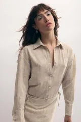Vestido camisero color beige con estampado de líneas horizontales, con botones de nácar y sobrefalda integrada. Confeccionado en poliéster suave con leve rugosidad. Diseñado y confeccionado en Uruguay.