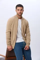 Campera tejida de lana color beige, con cuello alto, cierre metálico frontal y bolsillos laterales. Presenta detalles en cuero y logo bordado en el pecho.