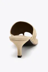 Sandalia color beige de ante, estilo mule, con tira ancha arrugada y posición para el dedo. Tacón fino medio y acabado en punta redonda.