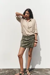 Falda pantalón verde militar con lentejuelas plateadas y negras, de tiro alto, con delantero cruzado y nudo.