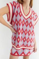 Chaleco tejido de lana con patrón de rombos en tonos lila, rojo y beige, con cuello en V y ribetes en color crema. Diseño oversize.