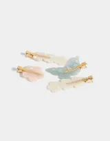 Set de cuatro hebillas para el pelo con forma de flor y mariposa, en tonos pastel y dorado.
