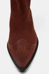 Botín de mujer estilo cowboy color marrón de cuero serraje con puntera fina, tiradores laterales y tacón de 5 cm.