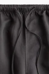 Pantalón recto gris oscuro de tejido vaporoso en mezcla de lino. Modelo holgado con elástico y cordón de ajuste en la cintura, bolsillos laterales y traseros insertados.