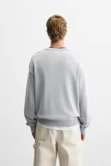Sweater negro de algodón con cuello redondo y mangas largas. Tiene un acabado lavado con efecto desgastado y rib en cuello, puños y bajo.