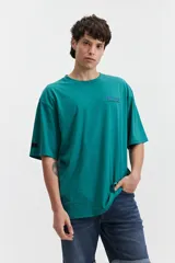 Remera de manga corta color salmón, de corte holgado con estampado en la espalda que incluye una flor con cara y texto.