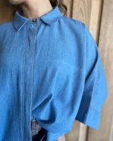 Camisa celeste de mangas largas con cuello clásico y cierre frontal con botones.