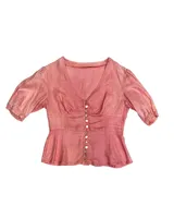 Camisa color amarillo pálido con corte en la cintura y abotonadura central. Tiene manga abullonada con detalle de elástico en puños.