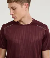 Remera deportiva de manga corta y cuello redondo, color beige claro, con textura acanalada vertical. Presenta detalles reflectantes en los hombros.