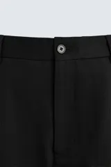 Pantalón negro de algodón con corte relajado y pierna ancha (flare fit). Presenta cierre frontal con botón y cremallera, bolsillos delanteros y bolsillos traseros de plastrón.