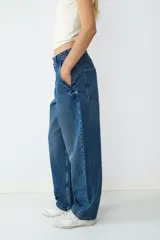 Pantalón jean azul oscuro de corte ancho, estilo skater, con cierre de cremallera y botón, y cuatro bolsillos.