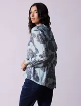 Camisa de gasa estampada a rayas verticales de color celeste, blanco, naranja y marrón. Tiene cuello con solapa, escote en V, abertura central con botones, bolsillo aplicado en el pecho y terminación anudada en la parte delantera.