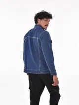 Campera de jean azul con cuello clásico, cierre frontal con botones metálicos, bolsillos con solapa abotonada en el pecho y bolsillos laterales.
