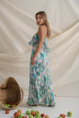 Vestido largo de gasa plisada con estampado floral en tonos verde, celeste, blanco y rosa. Diseño strapless con volado en el corsé, corte en la cintura y falda amplia.