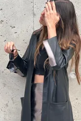 Tapado largo de cuero negro con cuello desmontable y detalles en peltre en las mangas. El cuello desmontable es reversible, de un lado peltre y del otro marrón.