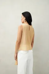 Top blanco de tencel sin mangas, de corte asimétrico, con volados en diagonal.