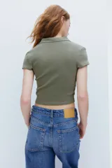 Remera polo verde oliva en punto de algodón acanalado, de manga corta con cuello clásico y tapeta de botones. Corte entallado.