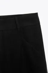 Pantalón color ladrillo de tiro medio con trabillas, detalle de pliegues, bolsillos laterales y falsos bolsillos de vivo en la espalda. Cierre frontal con cremallera y botón.