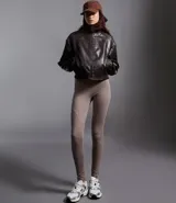 Campera bomber femenina de cuero sintético color marrón oscuro, con cuello alto, frisos en los hombros, puños y bajo ajustados, y cierre delantero con cremallera.