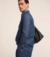 Camisa de hombre de tejido plano de algodón, color celeste claro, con cuello solapa, manga larga y bolsillo simple en el pecho izquierdo.