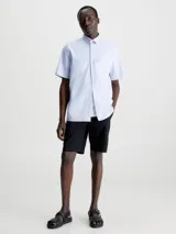 Camisa celeste de popelín de algodón superelástico, con cuello en punta, manga corta, tapeta con botones y logo con monograma de Calvin Klein en el pecho.