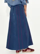 Pollera larga de jean azul con corte acampanado y costuras verticales en color ladrillo.