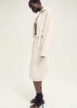 Falda midi color crudo, de corte recto y tiro medio. Presenta un forro interior visible de ramio y cintura con goma elástica.