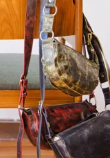 Bandolera de cuero color rojo con detalles en negro, con correa regulable y cierre superior con cremallera.