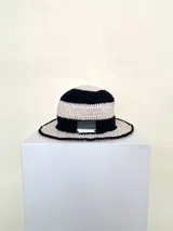 Sombrero tipo bucket tejido a crochet a mano, con hilo 100% algodón y diseño a rayas en tonos rosa y rojo. Presenta una etiqueta con el logo de la marca Cilento en el frente.